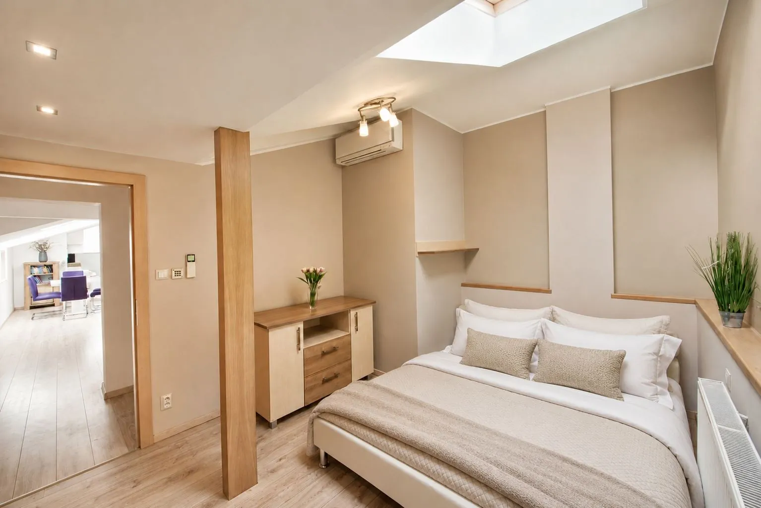 Guest bedroom with a queen bed under a skylight, air conditioning and a radiator